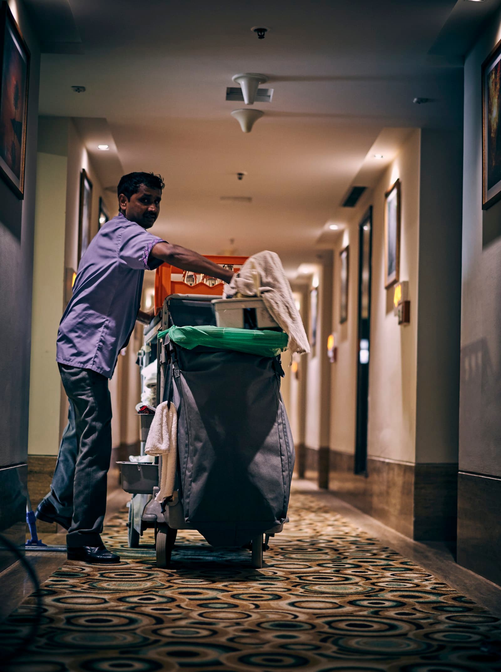 Cleaner with a cleaning cart in an office corridor