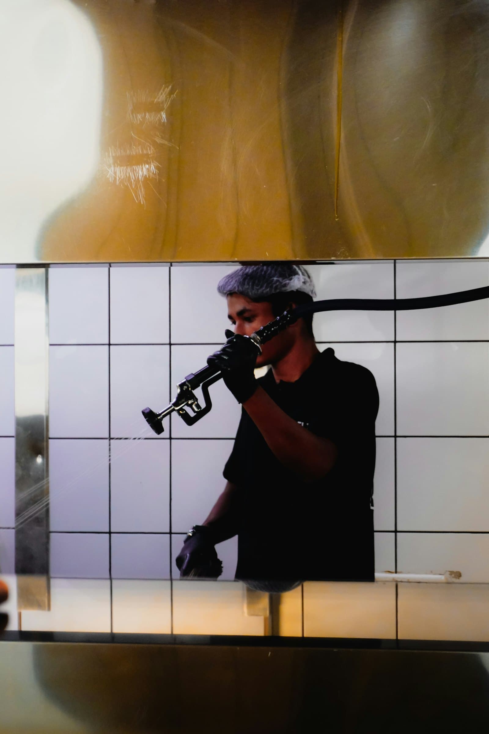 Cleaner spraying down a tiled commercial kitchen wall